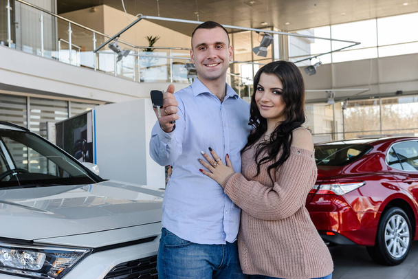 Beautiful and young couple with car keys in salon - Zdjęcie, obraz