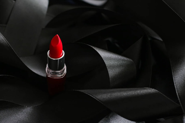 Lápiz labial rojo sobre fondo de seda negro, maquillaje de lujo y cosméticos de belleza - Foto, Imagen