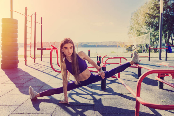 Mujer atleta bonita haciendo ejercicios matutinos en el patio de recreo de la calle. Entrenamiento al aire libre. Entrenamiento de mujeres - Foto, imagen