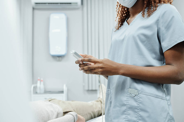 Крупный план неузнаваемой медсестры в хирургических перчатках, заполняющей карточку пациента в больнице - Фото, изображение
