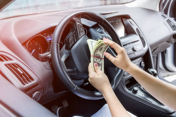 Manos femeninas con bulto de dólar en el volante de cerca. Soborno y corrupción - Foto, imagen