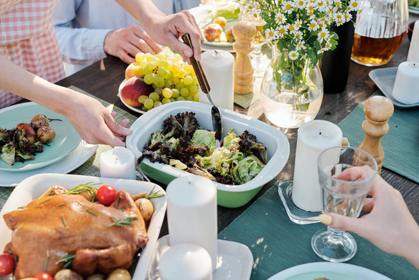 Hände von jungen Frauen mit Löffel nehmen oder mischen gekochtes Gemüse auf festlichem Tisch serviert mit hausgemachten Speisen unter Freunden - Foto, Bild