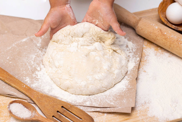 dough in flour kneading childrens hands, one kid, child helps parents in kitchen, concept of a happy childhood, household help, homework, food preparation - Fotoğraf, Görsel