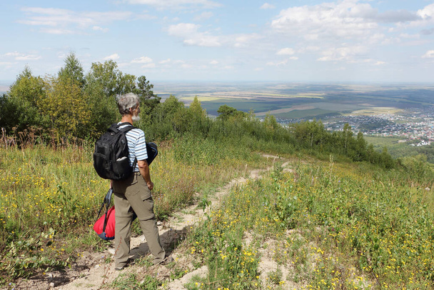 Man with a backpack descending the trail  from  the mountain Tserkovka, Belokurikha city, Altai, Russia - Zdjęcie, obraz