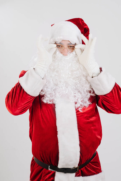 Portrait of a surprised Santa Claus in red clothes, holding glasses with his hands. High quality photo - Fotoğraf, Görsel