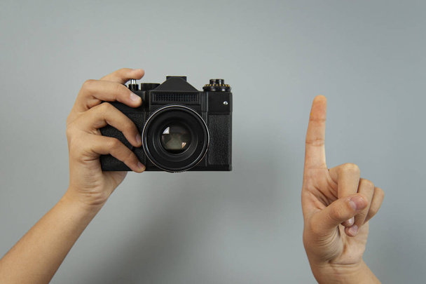 Παλιά κάμερα σε γυναικεία χέρια σε γκρι φόντο - Φωτογραφία, εικόνα