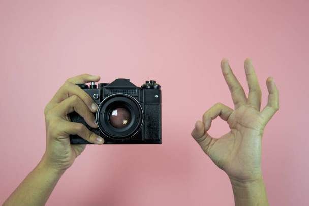 Vecchia macchina fotografica in mani femminili su sfondo rosa - Foto, immagini
