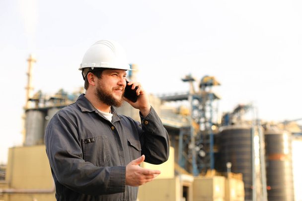 Retrato del director industrial hablando por VHF walkie talkie cerca de la fábrica exterior. - Foto, imagen