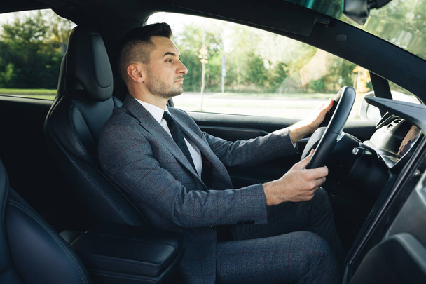 Portrait of successful start-up developer engineer boss executive on drive. Handsome young businessman in car. People and transportation - Zdjęcie, obraz