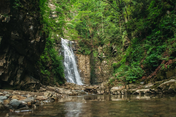 Wasserfall mit See zwischen Felsen und Wald - Foto, Bild