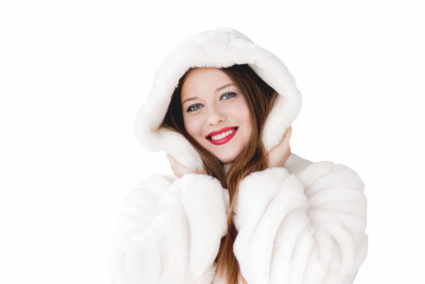 Mujer joven con abrigo de piel esponjosa con capucha, ropa de invierno cálido para la moda y las vacaciones de Navidad - Foto, imagen