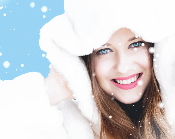 Natal e inverno férias retrato de jovem mulher de casaco de pele com capuz branco, neve no fundo azul, moda e estilo de vida - Foto, Imagem