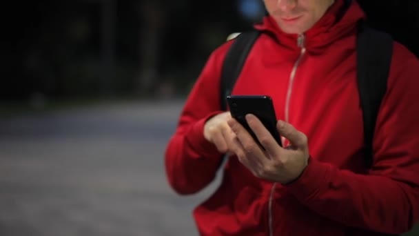 Nierozpoznawalna osoba ze smartfonem w parku - Materiał filmowy, wideo