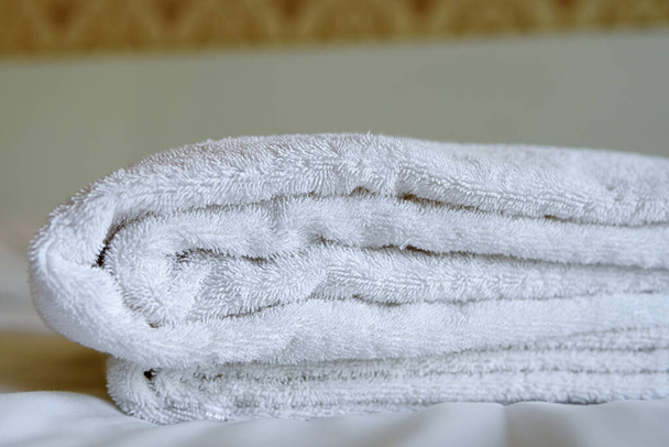 Білі банні рушники на ліжку в готелі
. - Фото, зображення