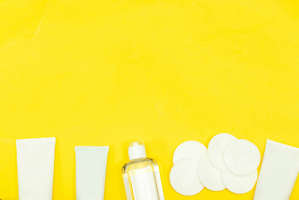 Make-up entfernt Hautpflege. Tonic für Gesichtshaut oder Make-up-Entferner in einer Plastikflasche, Wattepads und Cremetubus auf gelbem Hintergrund. Hygieneartikel, Beauty-Werkzeuge und Haut - Foto, Bild