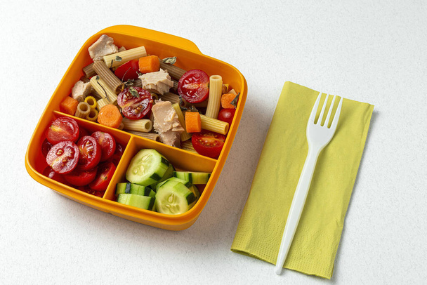 Lunch at work place healthy pasta with tuna, cherry tomatoes, carrot, cucumber in lunch box on work table. Home food for office concept - Fotografie, Obrázek