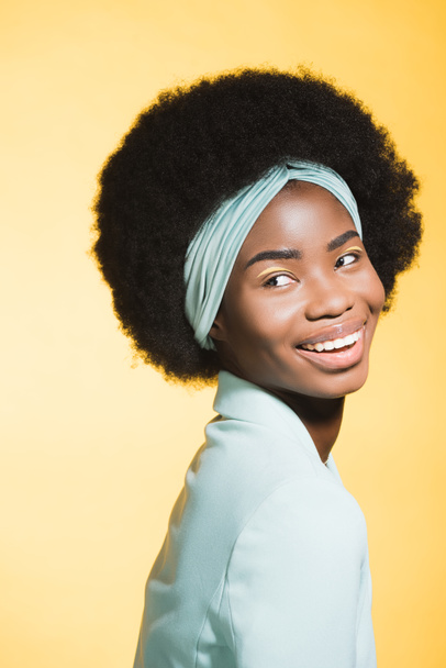feliz afroamericana joven mujer en azul elegante traje aislado en amarillo  - Foto, Imagen