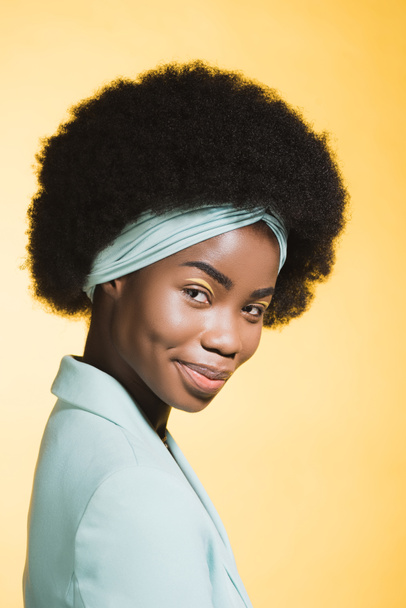 smiling african american young woman in blue stylish outfit isolated on yellow  - Fotoğraf, Görsel