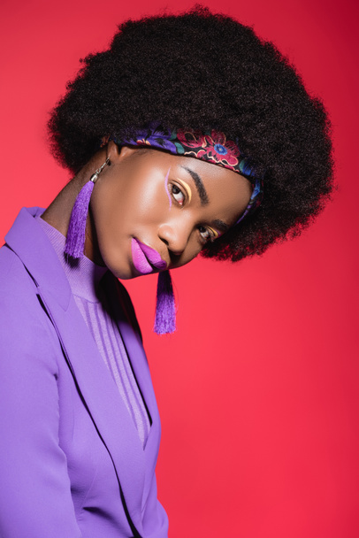 afro-américaine jeune femme en violet tenue élégante isolé sur rouge - Photo, image