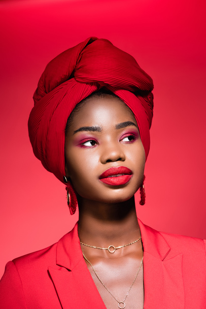 african american young woman in stylish outfit and turban isolated on red - Photo, image