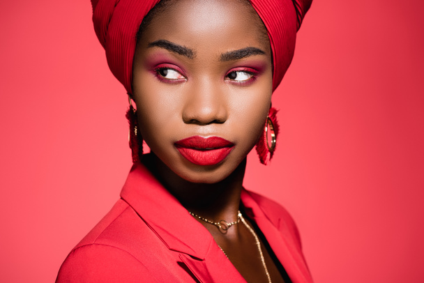 mujer joven afroamericana en traje elegante y turbante aislado en rojo - Foto, imagen