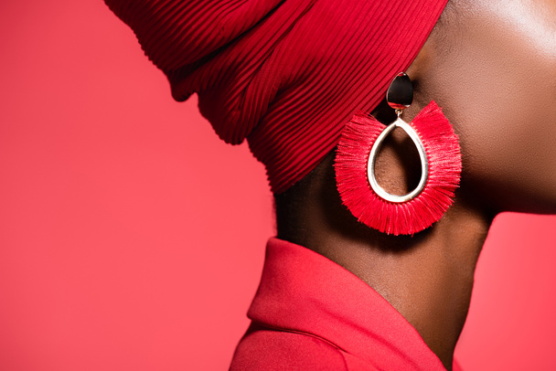 oříznutý pohled na africkou americkou mladou ženu ve stylové náušnici izolované na červené - Fotografie, Obrázek
