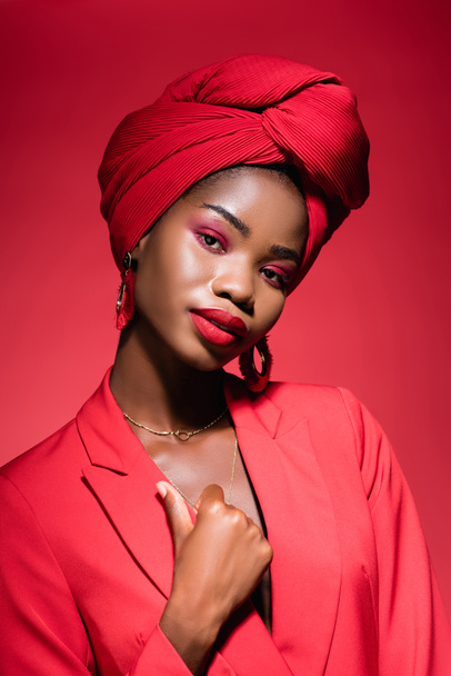 african american young woman in stylish outfit and turban isolated on red - Zdjęcie, obraz