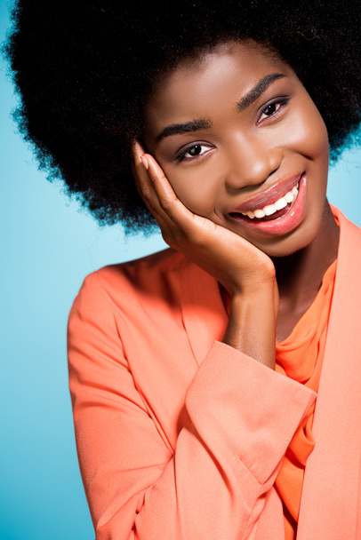 sorridente Africano americano jovem mulher em laranja elegante roupa isolada em azul - Foto, Imagem