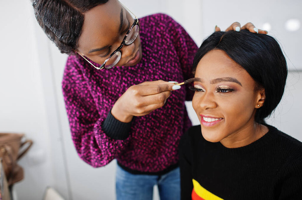 African American woman applying make-up by make-up artist at beauty saloon. - Photo, Image