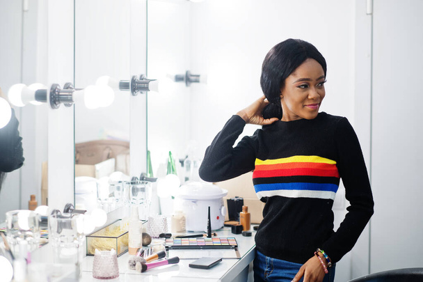 Portrait of African American woman applying make-up at beauty saloon. - Fotó, kép