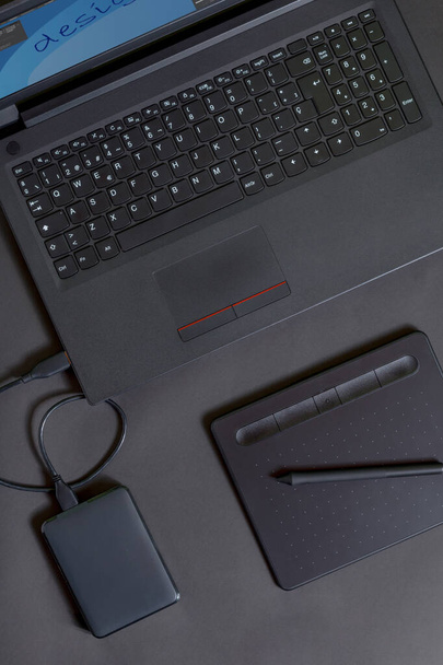 Tableta de lápiz, con un ordenador portátil y un disco duro sobre un fondo negro - Foto, Imagen