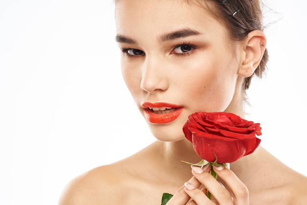Όμορφη γυναίκα με κόκκινο τριαντάφυλλο κοντά μακιγιάζ πρόσωπο γυμνοί ώμοι πορτρέτο - Φωτογραφία, εικόνα