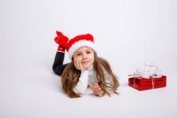 niedliches Kind posiert in Weihnachtsmütze und mit Geschenkbox - Foto, Bild