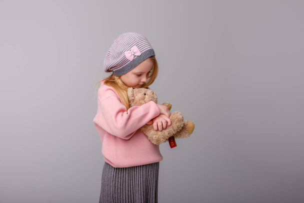 Nettes Mädchen posiert mit Teddybär gegen Grau - Foto, Bild