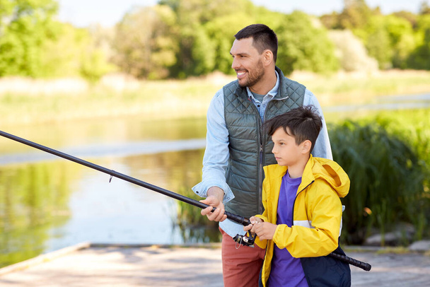 happy smiling father and son fishing on river - Foto, immagini