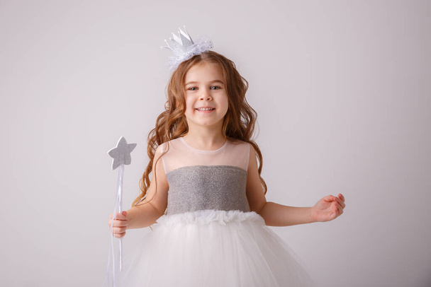 kislány tündér jelmezben, hercegnő lány kezében egy varázspálca mosolyog, elszigetelt fehér háttér  - Fotó, kép