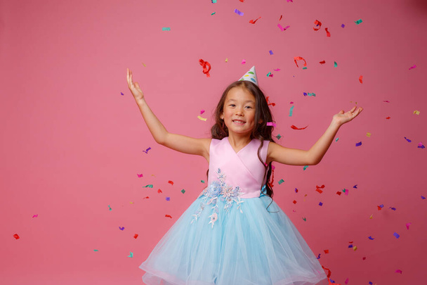 Asiatisches Mädchen feiert Geburtstag Schläge fängt Konfetti auf rosa Hintergrund - Foto, Bild