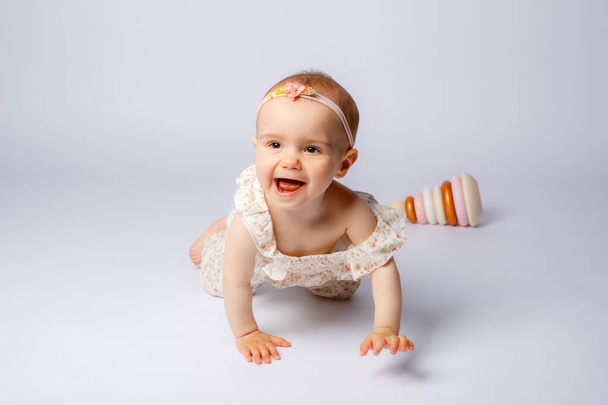baby girl portrait playing with wooden toys dishes on a white background - Photo, Image