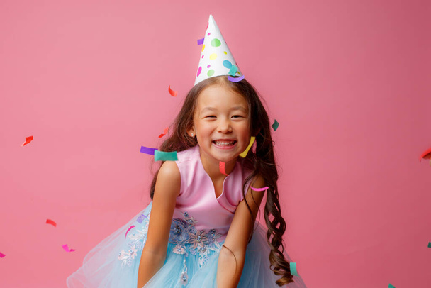アジアの女の子お祝いの誕生日打撃キャッチconfettiオンピンクの背景 - 写真・画像