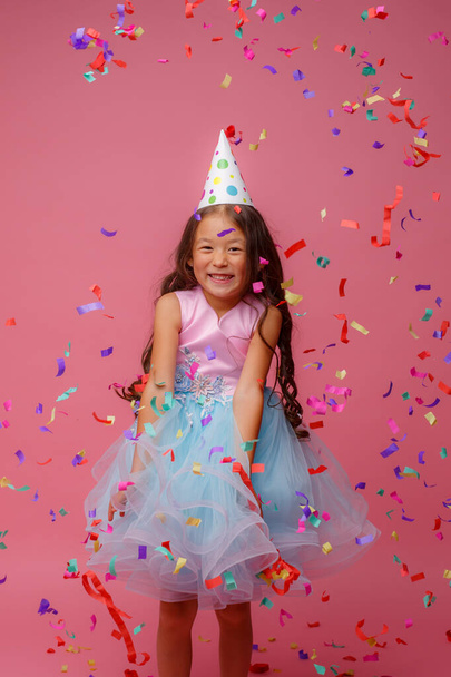 asiático chica celebra cumpleaños golpes capturas confeti en rosa fondo - Foto, imagen