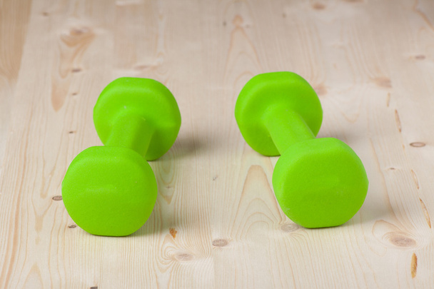 Small green dumbbells on wooden surface - Фото, зображення