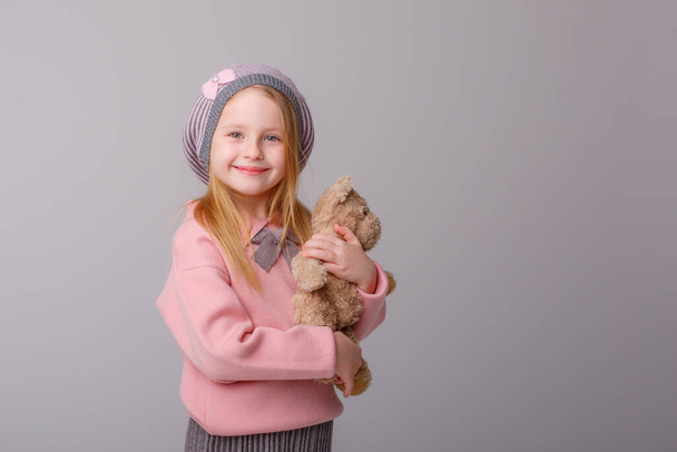 cute girl posing with teddy bear against gray - Foto, Bild