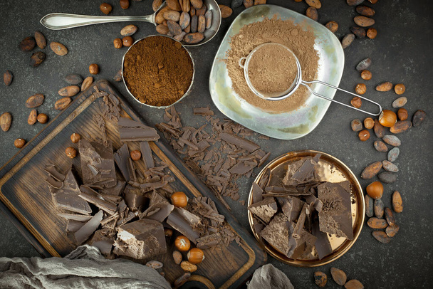 Stücke von dunkler Schokolade und Kakaobohnen in Komposition auf altem Hintergrund - Foto, Bild