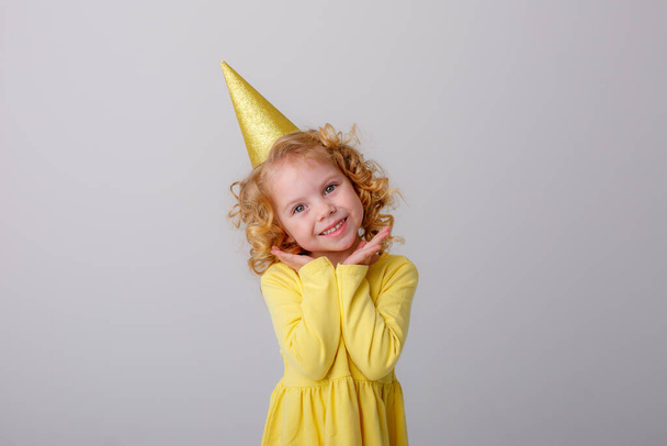 niña feliz vestido amarillo y sombrero de cumpleaños - Foto, Imagen