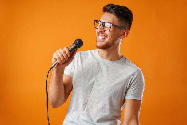 Hispanic young handsome man singing with joy in microphone - Zdjęcie, obraz