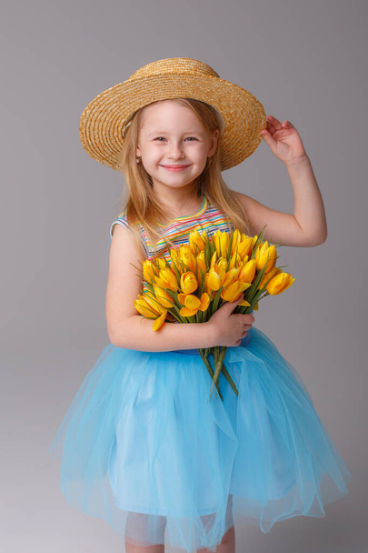 cute little girl posing in studio with yellow tulips - Foto, afbeelding