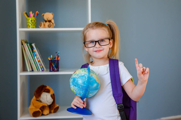 красивая маленькая девочка из начальной школы держит глобус  - Фото, изображение