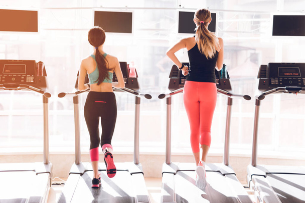 Girls run in the gym on treadmills together. - Zdjęcie, obraz