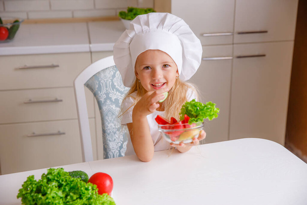Aşçı şapkası takan sevimli küçük kız yemek yapmaya hazırlanıyor. - Fotoğraf, Görsel