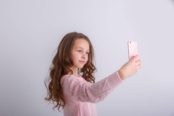 Pembe kazaklı, selfie yapan güzel bir kızın portresi. - Fotoğraf, Görsel